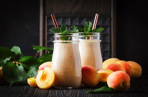 Batidos de albaricoque con frutas y semillas de lino en botellas de vidrio mesa de cocina rústica oscura lugar de fondo para el enfoque selectivo de texto