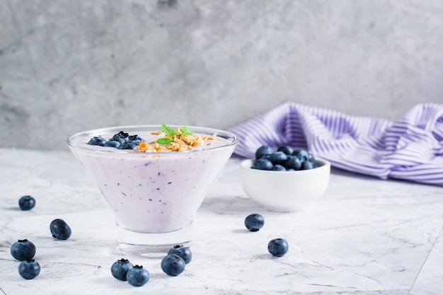 Batidos con arándanos y granola en un recipiente sobre la mesa Alimentos saludables antioxidantes orgánicos