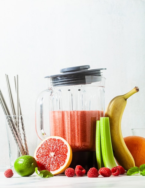 Batidos en un bol de licuadora de vidrio e ingredientes sobre la mesa.