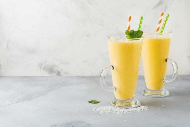 Batidos de calabaza con jengibre y virutas de coco y menta en un vaso sobre piedra clara o fondo de hormigón Bebida saludable y deliciosa para el desayuno