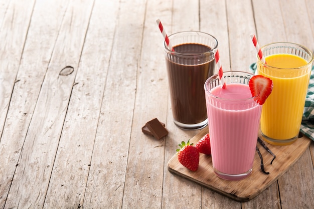 Batidos de chocolate, fresa y vainilla en la mesa de madera rústica