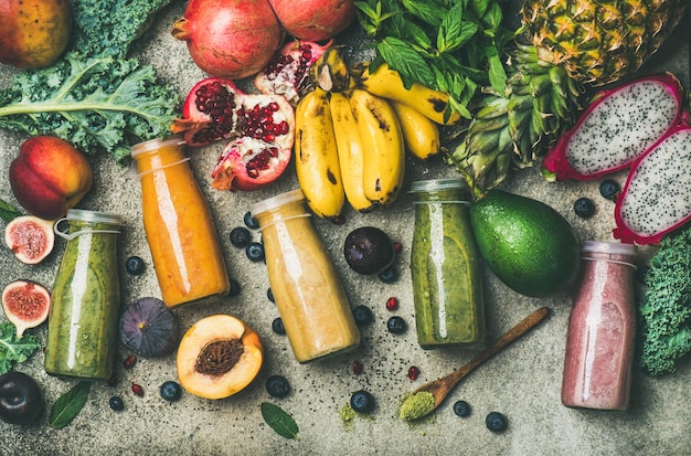 Batidos coloridos en botellas con frutas tropicales frescas y superalimentos