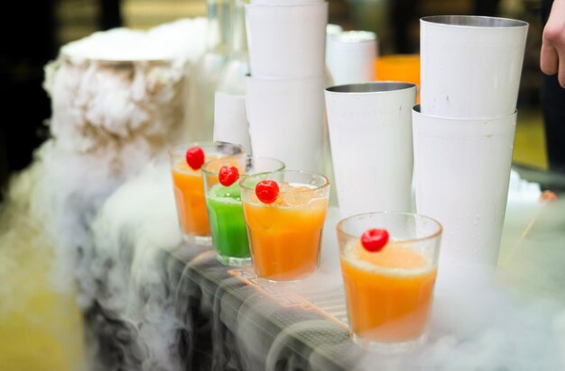 Batidos coloridos en vasos de vidrio a la venta en un mostrador de bar En una nube de nitrógeno