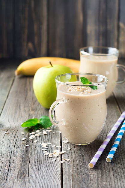 Foto batidos de banana de maçã com aveia na superfície de madeira velha. foco seletivo.