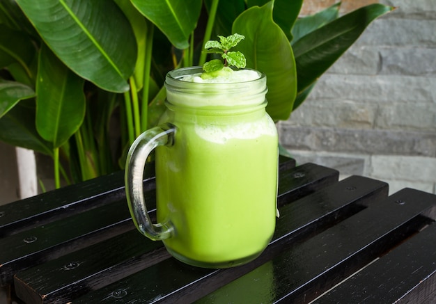 Batidos do chá verde no vidro na tabela de madeira preta.