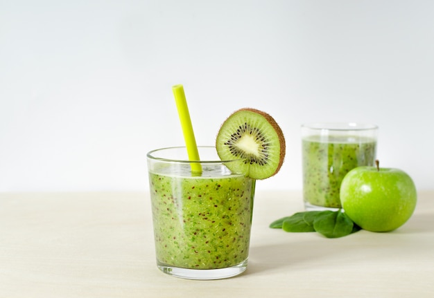 Batidos de kiwi, manzana y espinacas. batido verde en un vaso con kiwi y paja.