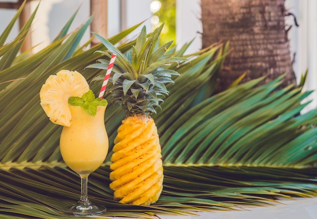 Batidos de piña y piña contra la superficie de una rama de una palmera