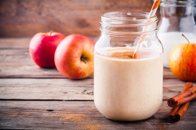 Batidos saludables para el desayuno con manzana roja y canela en un tarro de vidrio sobre un fondo de madera