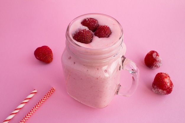 Batidos con yogur y fresa congelada sobre fondo rosa