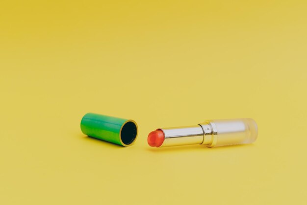 Batom com tampa verde brilhante sobre fundo amarelo