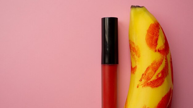 Batom vermelho em uma banana amarela em um fundo rosa. Conceito de amor e sexo.