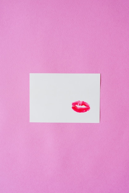 Batom vermelho lábio impressão beijo na folha de papel branco em fundo rosa