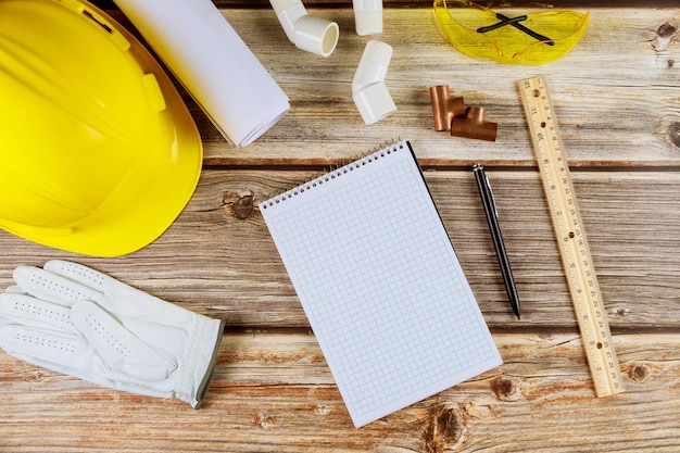 Bau auf Bauplänen mit Werkzeugen und Helm auf Notebook mit Stift mit Arbeit