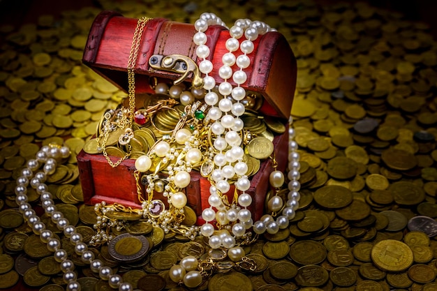 Baú do tesouro vintage cheio de moedas de ouro e joias em um fundo de moedas de ouro