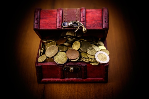 Baú do tesouro vintage cheio de moedas de ouro em fundo de madeira