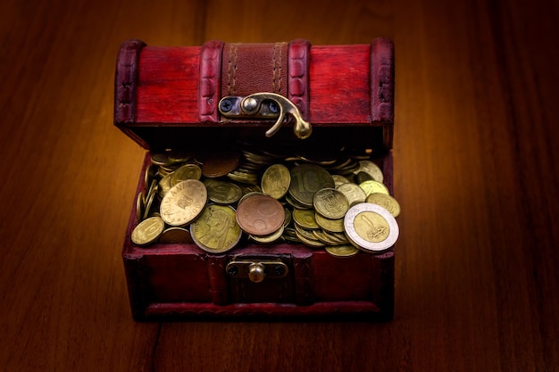 Baú do tesouro vintage cheio de moedas de ouro em fundo de madeira