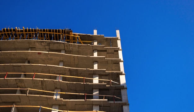 Bau eines modernen Gebäudes. Wohngebäude im Bau vor blauem Himmel Hintergrundfoto