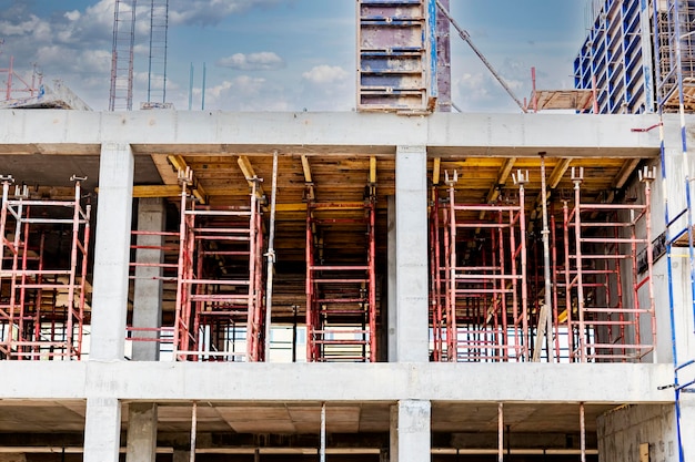 Bau eines neuen monolithischen stahlbetonhauses gerüst an der fassade eines im bau befindlichen gebäudes arbeiten in der höhe auf einer baustelle