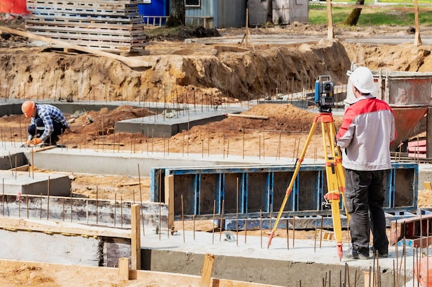 Bau eines Wohngebietes Geodätische Absteckung Landvermesser auf einer Großbaustelle Ein Mann mit Drehzahlmesser bei der Arbeit Makshader