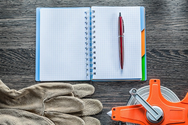 Bau Maßband Schutzhandschuhe Notebook Stift auf Holzbrett