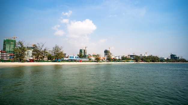 Bau von mehrstöckigen Gebäuden in Kambodscha, Sihanoukville. Moderne Hochhäuser im Bau. Strand mit weißem Sand in der Stadt. Viele Kräne am Ufer.