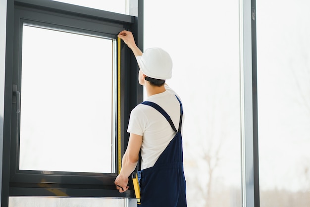 Bauarbeiter, der ein Fenster in einem Haus installiert