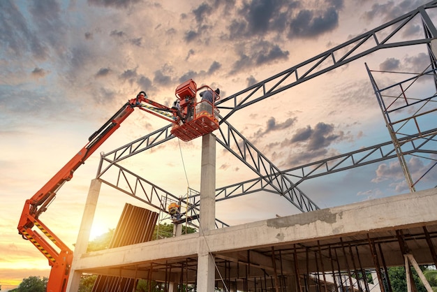 Bauarbeiter, die an Baumaschinen arbeiten Hubarbeitsbühne für Arbeiter, die in der Höhe an Gebäuden arbeiten