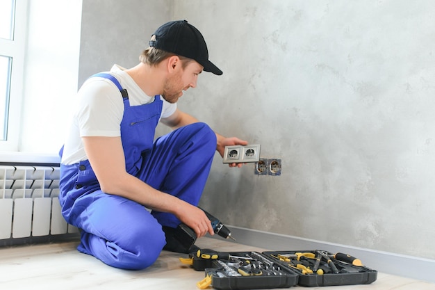 Bauarbeiter-Elektriker montiert eine Steckdose in einer Wohnung