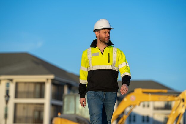 Bauarbeiter in der Nähe von Bagger Bauarbeiter mit Bagger Bauarbeiter in Helm Arbeiter in Hardhat Porträt mechanischer Arbeiter in Bauhelm Ingenieur Baumeister Vorarbeiter oder Reparateur