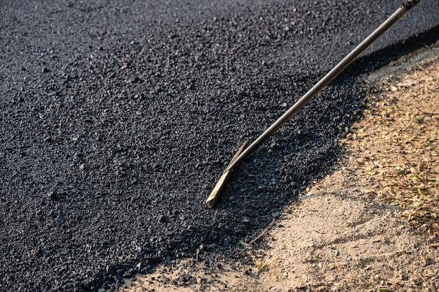 Bauarbeiter mit Werkzeug verteilen den Hotmix-Asphalt