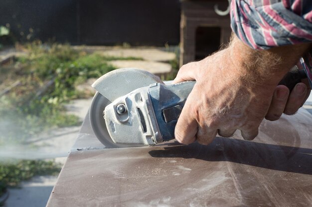 Bauarbeiter schneiden Betonplatte für Zaunfundament mit einer Trennsäge