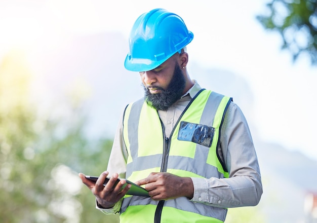 Bauarbeiter-Tablet und Gebäudeinspektionsprüfung mit Industrieangestellter mit Technik Afrikaner männliche Person professionelle und Baumeisterforschung mit Website und App für Ingenieur Projekt Outdoor