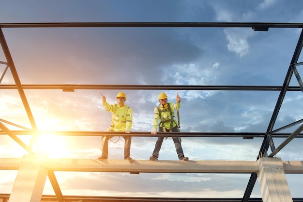 Bauarbeiter tragen Sicherheitsgurte und Sicherheitsgurte, die auf industriellen Metalldächern arbeiten