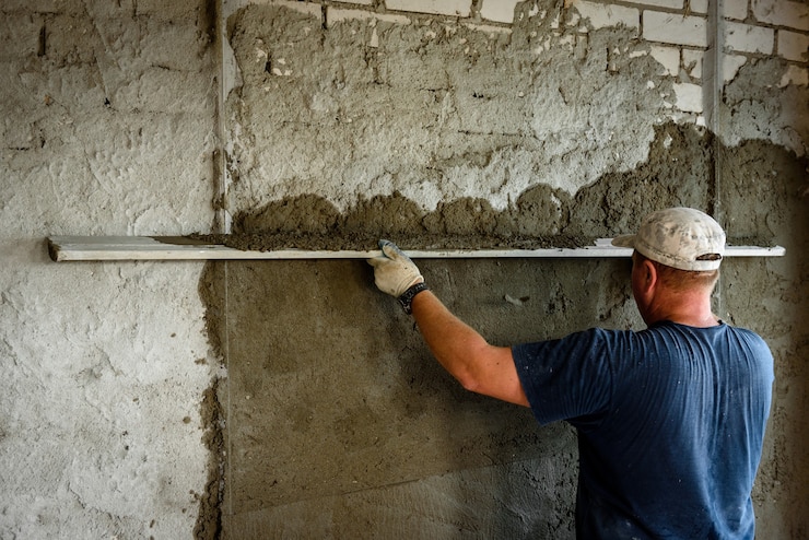 Foto bauarbeiter verputzt wand mit richtmaschine.