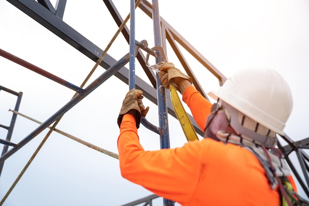 Bauarbeiter verwenden Sicherheitsausrüstung, um Stürze aus der Höhe zu verhindern, oder eine Fallschutzvorrichtung für Arbeiter mit Haken für Sicherheitsgurte auf der Baustelle