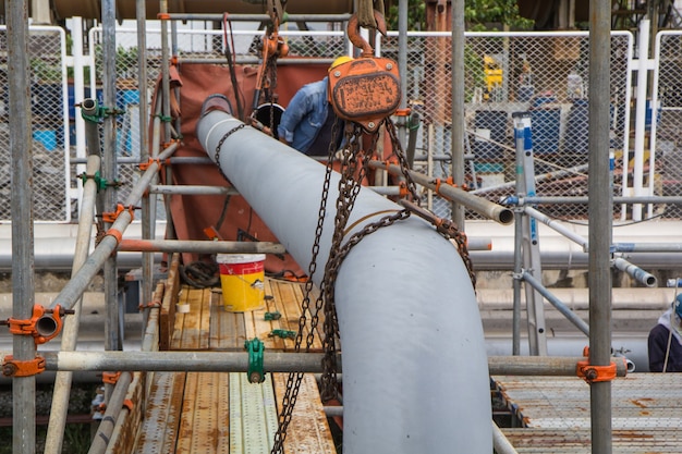 Bauarbeiterkettenzug, der Rohrventile in der Öl- und Gaspipelineindustrie auf der Baustelle installiert