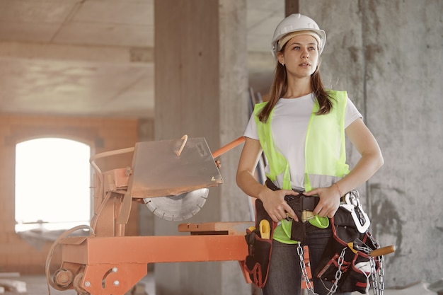 Bauarbeitermädchen mit Sicherheitsgurt und Werkzeugtasche auf der Baustelle