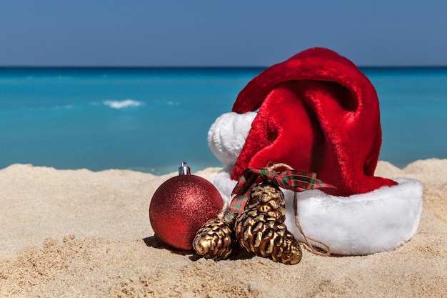 Bauble y el sombrero de Santa en la orilla en la playa durante un día soleado
