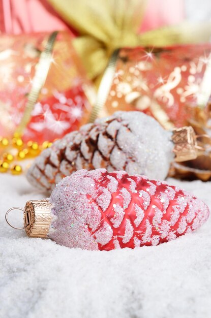 Baubles de cones de abeto de Natal na neve sobre um fundo brilhante