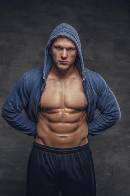 Bauchstarker Mann in einem blauen Hoodie auf grauem Hintergrund.