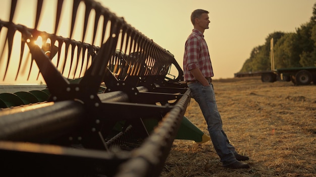 Bauer entspannt goldenes Feld allein am Mähdrescher. Agribusiness-Konzept