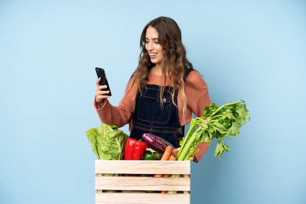 Bauer mit frisch gepflücktem Gemüse in einer Schachtel, die ein Selfie macht