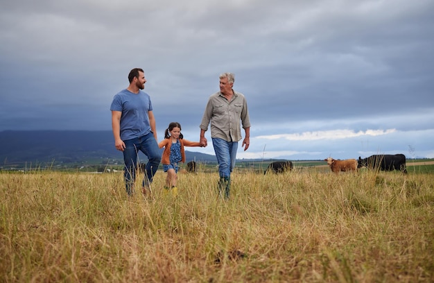 Bauernfamilie, die auf einem Rinder- oder Viehhof spazieren geht, gemeinsam lehren und lernen Generationen eines glücklichen Vaters, Großvaters und Enkelkindes, die sich auf nachhaltiger Landwirtschaft verbinden