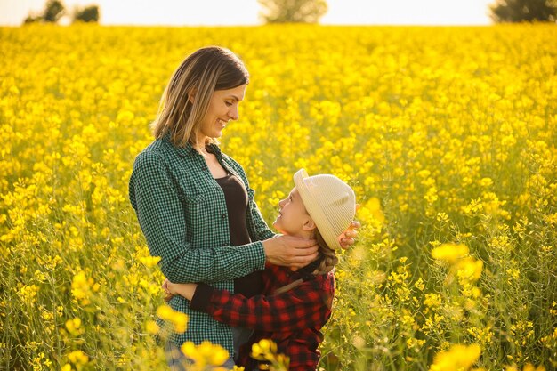 Bauernfamilie Mutter und Tochter umarmen sich in Sommerhemd, lachen und lächeln bei Sonnenuntergang