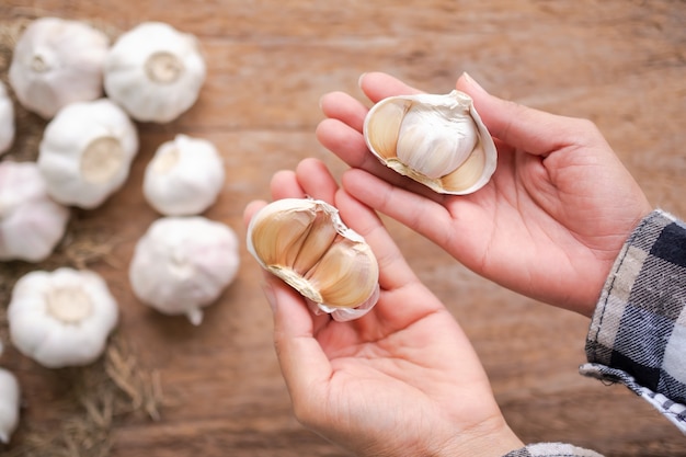 Bauernhände und Knoblauch auf Holz Blud Hintergrund halten