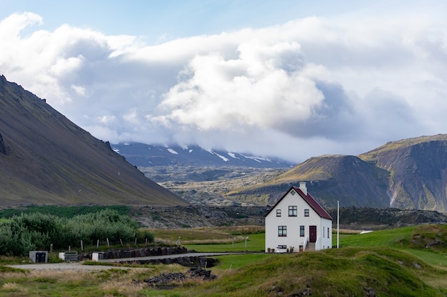 Bauernhaus auf Hügel in Island mit bewölktem Himmel und schöner Ansicht auf Hintergrund