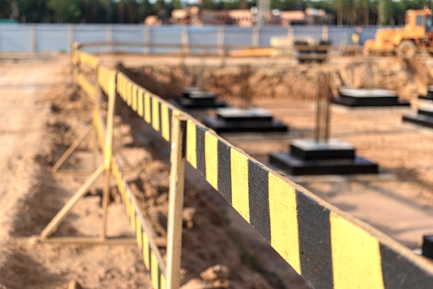 Baugrubenzäune. Bausicherheit. Baustelle mit Stahlbetonfundamenten mit Schutzzaun.