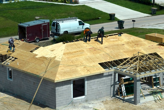 Foto bauherren, die an der dachkonstruktion eines unfertigen wohnhauses mit holzrahmenkonstruktion in einem vorort von florida arbeiten wohnentwicklungskonzept