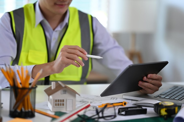 Foto bauingenieur mit digitalem tablet, während er am arbeitsplatz sitzt konzept der bauarchitektur