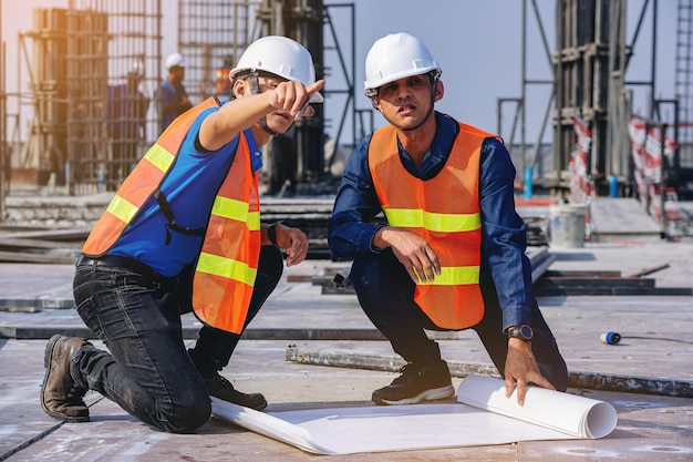 Bauingenieur und Vorarbeiter mit Bauplänen besprechen Planprüfung für das Gebäude